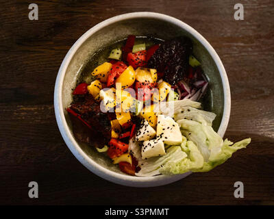 Choban salad of cucumbers, tomatoes, bell peppers and cheese in a white plate on an isolated wooden background Stock Photo