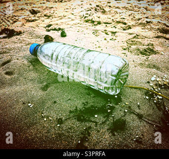 water bottle waste trash on the sand on the beach pollution Stock Photo