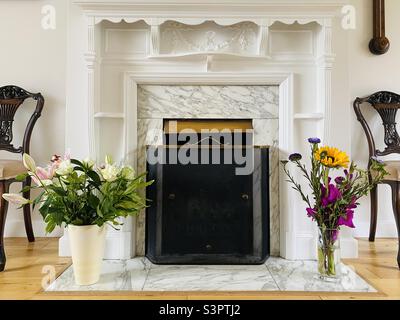 Pretty fireplace with two vases of flowers on the Hearthstone Stock Photo