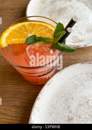 Grapefruit cocktail with a slice of orange and mint.  Cocktail with ice and straws Stock Photo