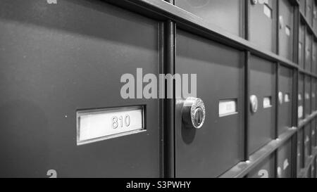 Close up detail of locked mail boxes with focus on foreground number. Black and white Stock Photo