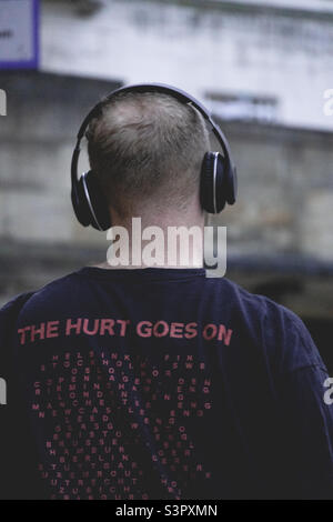 Rear view of male wearing headphones and listening to rock music Stock Photo