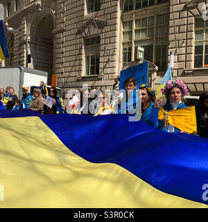 23 April, 2022, people hold a giant Ukrainian flag at the Arm Ukraine Now rally, Bowling Green, New York, New York, United States Stock Photo