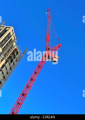 Large red crane at a construction site against a clear blue sky. Stock Photo