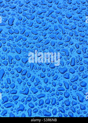 Arbitrary water droplets have settled on a blue metallic surface. An interesting image with lots of potential uses? Photo ©️ COLIN HOSKINS. Stock Photo