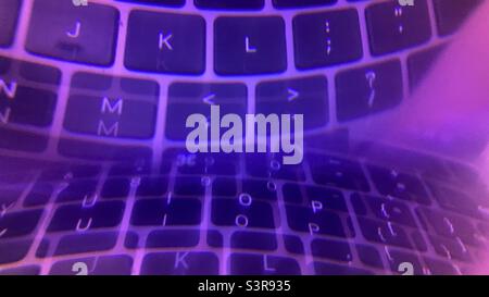 Colorful abstract pattern created with prism in front of camera lens. Letters on a computer keyboard reflected and refracted with purple hue Stock Photo