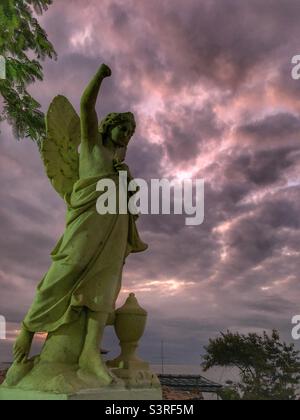 An angel statue against a beautiful intense sky of purple hues. Stock Photo