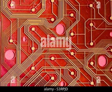 A detail of a printed circuit from an old keyboard against a red background Stock Photo