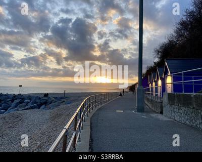 Sun setting over the beach with beach huts  near Folkestone in Kent Stock Photo