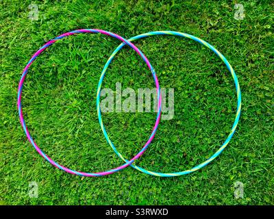 Two overlapping hula-hoops on grass. A Colorful, stylized VENN figure. Two intersecting circles. Contours. Stylish. Minimalist Stock Photo