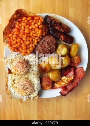 Monster brunch- eggs, sausages, bacon, potatoes, beans, toast and a burger. Stock Photo