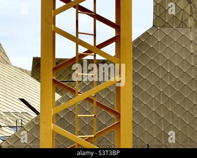 The lattice work of a yellow painted crane on a building site in Worcester UK with The Hive in the background. Stock Photo