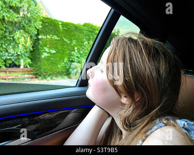 Young 12 year old girl looking out of car window Stock Photo