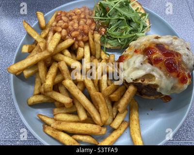 Homemade Spicy Cheese Burger, Chilli Jam, Cajian Fries, Rocket, on a bun with BBQ beans Stock Photo