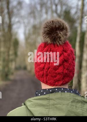 Rear view of woman wearing a knit hat walking in woodlands Stock Photo