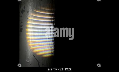 Pattern on grungy metal pole created by light with diffraction patterns and a lens causing chromatic aberration. Texture or abstract background with space for copy Stock Photo