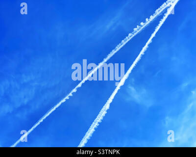 Two vapour trails in a blue sky. An abstract image of aviation. Did those aircraft collide? Have a near miss? Cross over with plenty of time to spare? Photo ©️ COLIN HOSKINS. Stock Photo