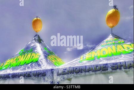 A pair of tent tops sport lemons on top advertising ice cold lemonade for sale at a local festival in Utah, USA. Color select and HDR effects added via IOS apps Snapseed and Color Splash. Stock Photo