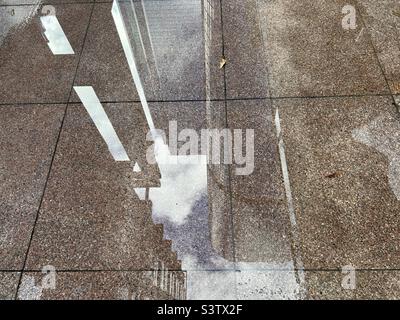 Skyscrapers reflected in a puddle of water on marble floor tiles Stock Photo