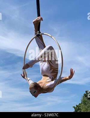 Female acrobat on suspended hula hoop in the park Stock Photo