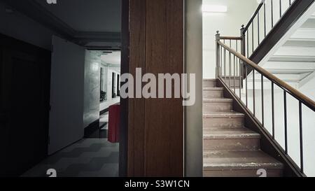 Split view of internal, fire escape staircase and a corridor receding into the distance in 1920s office building in Los Angeles, CA Stock Photo