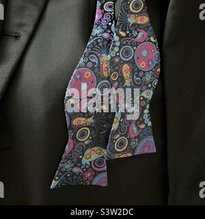 Undone bowtie with embroidered pattern, resting on a black tuxedo jacket, ready to be worn for a special event Stock Photo