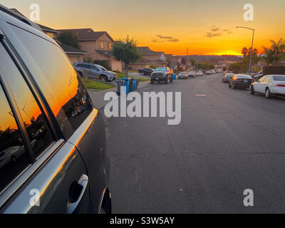 Orange sky at the end of a suburban street in Vallejo, California with and orange glow in the sky which reflects in the side of a car. Stock Photo