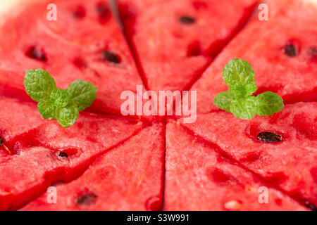 Macro shot of sweet juicy watermelon slices with fresh mint leaves, delicious healthy summer snack Stock Photo