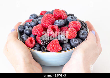 Bowl of fresh berries in hands, healthy breakfast option Stock Photo