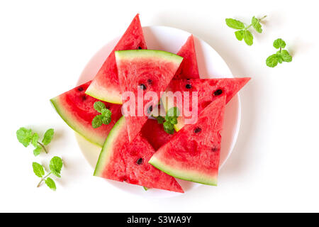 Fresh juicy watermelon on a white plate with mint leaves, top view Stock Photo