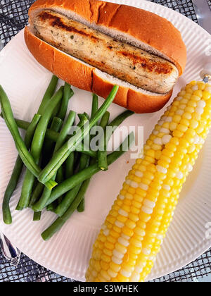 Healthy all American meal of corn on the cob, fresh green beans and chicken sausage and a hotdog bun, 2022, USA Stock Photo