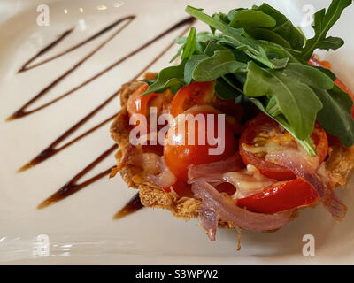 Tomato and bacon tartlet with rocket lettuce Stock Photo