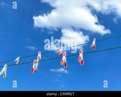Colourful pegs on a washing line against a blue sky with clouds. Stock Photo