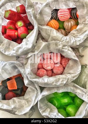 Traditional old fashioned sweets in paper bags rhubarb rock, soor plooms, midget gems, cinnamon balls, humbugs striped balls Stock Photo