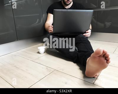 Young man using laptop and drinking coffee at home Stock Photo