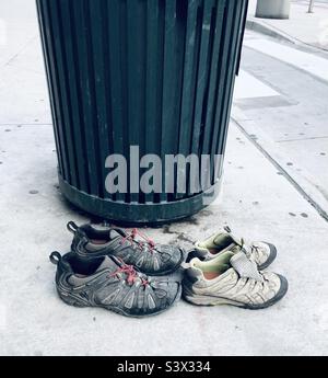 Two pairs of walking shoes left by a bin in the city of Denver Colorado USA Stock Photo