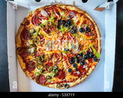 Mixed meat and veggie toppings on takeaway pizza Stock Photo
