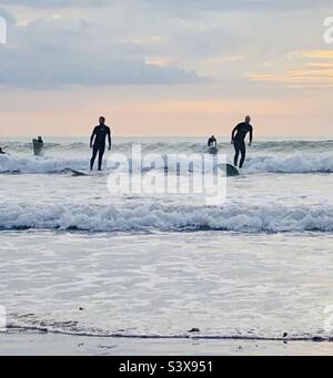 Surfers ride the waves at Saunton Sands in Devon England Stock Photo