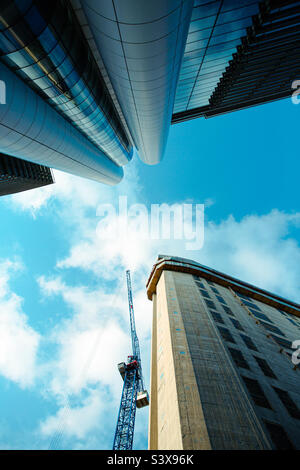 Low angle view looking up to tall skyscrapers in the city environment and construction site with crane in a new build Stock Photo