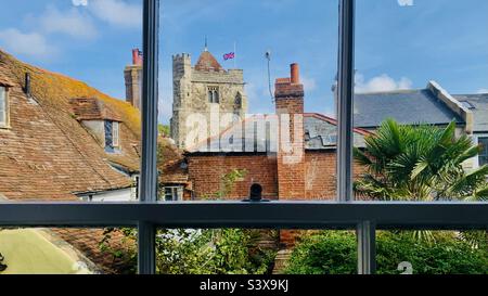 A sash window view of Hastings Old Town rooftops and church just days after the passing of the Queen ERII withe Union Flag at half mast Stock Photo