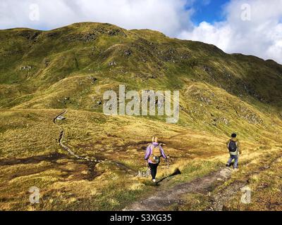 Walkers on the path up towards the Tarmachan ridge, Killin, Scotland Stock Photo