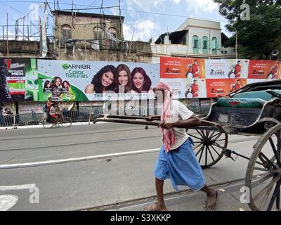 A manual rickshaw puller pulling rickshaw in the street of Kolkata Stock Photo