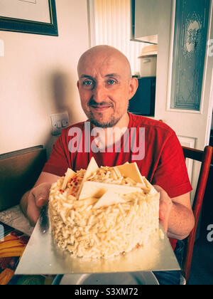 Man in late 40s celebrates another birthday with a white chocolate cake. Stock Photo