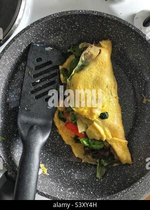 Home made omelette in pan with cheese, tomato and salad leaves Stock Photo