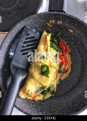 Home made omelette in pan with cheese, tomato and salad leaves Stock Photo