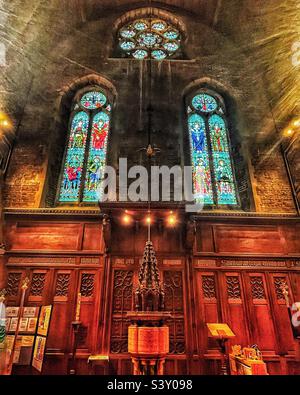 The font of 1907 is made up of polished marbles in the Holy Trinity Church in Folkestone, Kent. Grade II Listed historic building. Fine stained glass windows seen in situ 2022. Stock Photo