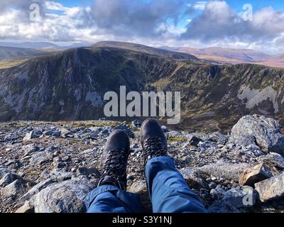 View of Walkers feet and leather boots on the Rocky slopes of the Cairnwell at Glenshee with a view towards The ridge of Creag a’ Choire Dhirich, Scotland Stock Photo