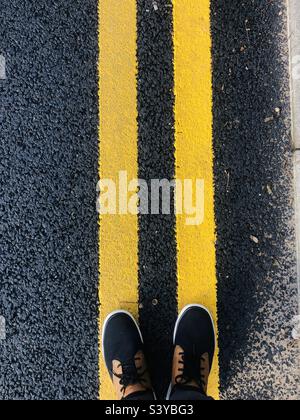 Person standing on yellow road lines Stock Photo