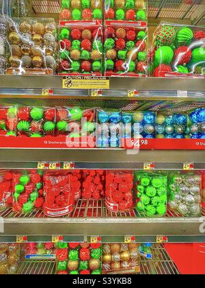 Shelves stacked high with new and modern  Christmas ornaments in shiny plastic packages for sale at a local Walmart in Utah, USA during the holiday season. Stock Photo