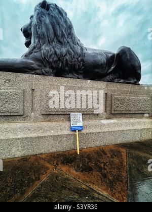 Discarded placard by the lion statue in Trafalgar Square in London says: “Freeze Rents and Service Charges Now” follows demonstration against Government plans for austerity measures in UK November 22 Stock Photo